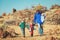 Father with three kids travel hiking in mountains