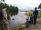 A father with three sons of different ages feed duck bread at a boat station on the lake