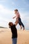 Father throwing daughter in the air at the beach