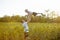 Father throws up his little son on sunny sunflowers field