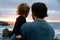 Father and toddler daughter watching the sunset over a rocky beach