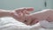 Father touching and counting his Newborn Baby`s little toes. Close Up. Parent Holding Newborns feet. Happy Parenthood.