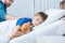 Father touching sick little son lying in hospital bed with teddy bear