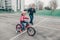 father training helping girl daughter to ride bicycle.