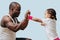 Father training his little daughter to box, making serious face. Over blue