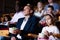 Father and tween daughter watching film together in cinema