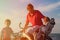 Father with two kids biking at sunset sea