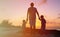 Father and two kids walking on beach at sunset