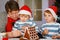 Father and two little sons preparing a gingerbread cookie house