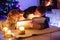 Father and two little toddler boys reading book by chimney, candles and fireplace. Family celebrating Christmas. With