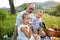 Father with two small children on meadow outdoors, having picnic.