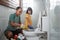 a father uses a toilet brush with his little daughter pouring a bottle of cleaning fluid while cleaning the toilet