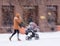 Father walks with the child in the stroller in snowy winter day. Intentional motion blur