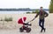 The father walks with his child in baby carriage in the park by