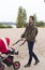 The father walks with his child in baby carriage in the park by