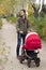 The father walks with his child in baby carriage in the park