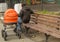 Father walks with his child in the pram, sitting on a bench in the Park