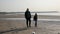 A father walks with his daughter and dog near the sea on a sandy beach