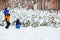 Father walks with his young children in the woods in winter