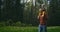 A father walks with his young son on his shoulders in a park against a backdrop of trees. Walking with a young happy