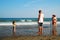 A father watches his toddler daughter as she plays on the beach