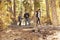 Father watching his two children walk over trees in a forest