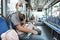 a father wearing a mask sits on a bench holding a small baby girl sleeping on the bus