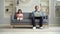 Father working with laptop and daughter playing on tablet in the living room