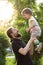 Fatherhood, parenthood, childhood, caring, summer and leisure concept - young dad with beard and long hair in black t