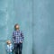 Fathers day square mockup. Dad and son standing together near blue wall and looking up. Parenting, two generations concept. Copy