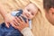 Fathers Hand on a Happy Mixed Race Baby Boy Laying on Blanket