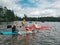 Fathers with kids swimming on paddle board on lake. Dads with children doing sport summer water activity outdoors. Seasonal