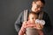 Fathre and his kid in baby carrier at the grey background wall, baby wearing concept