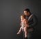 Fathre and his kid in baby carrier at the grey background wall, baby wearing concept