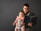 Fathre and his kid in baby carrier at the grey background wall, baby wearing concept