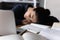 Fatigued young mixed race woman sleeping at workplace among books