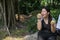 Fatty woman holding two hand and eating green  apple and sitiing on the stone at the park