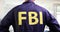 FBI agent in FBI uniform stands with back