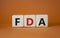 FDA - Food Drug Administration symbol. Wooden cubes with word FDA. Beautiful orange background. Medical and Food Drug