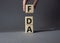 FDA - Food Drug Administration symbol. Wooden cubes with word FDA. Doctor hand. Beautiful grey background. Medical and Food Drug