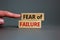 Fear of failure symbol. Wooden blocks with words `fear of failure`. Beautiful grey backgrounds. Businessman hand. Business, fear