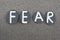 Fear word composed with black colored stone letters over volcanic sand