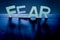 Fear. Word made by back lit letters on dark blue background with letters shadows.