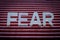 Fear. Word made by letters on red striped background.