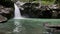 Fearless young man jumps into the waterfall spring in slow motion.