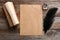 Feather pen, inkwell and blank parchment on wooden table, top view