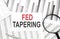 FED TAPERING text on paper with calculator,magnifier ,pen on the graph background