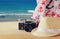 Fedora hat, old vintage camera and scarf over wooden table and sea landscape background. relaxation or vacation concept