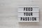 `Feed your passion` words on a modern board on a white wooden background, top view. Overhead, from above, flat lay. Copy space