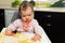 Feeding. Adorable baby child eating with a spoon in a children`s chair